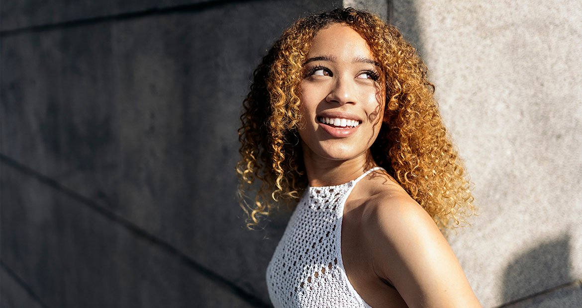 mulher negra de cabelo cacheados levemente claros